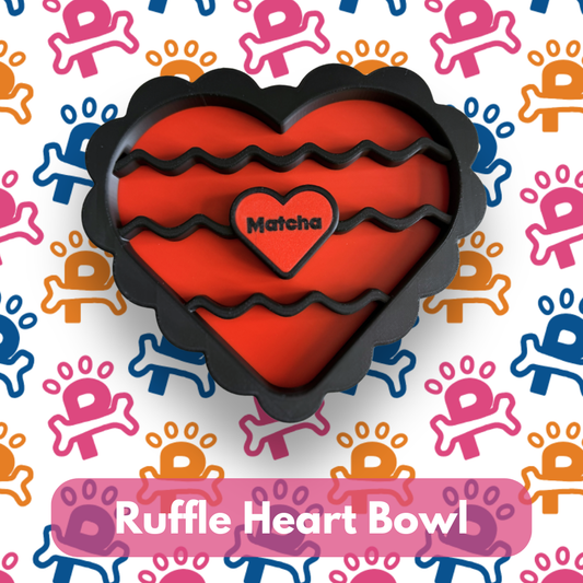Heart-shaped ruffle bowl with 'Matcha' text on a colorful paw print background
