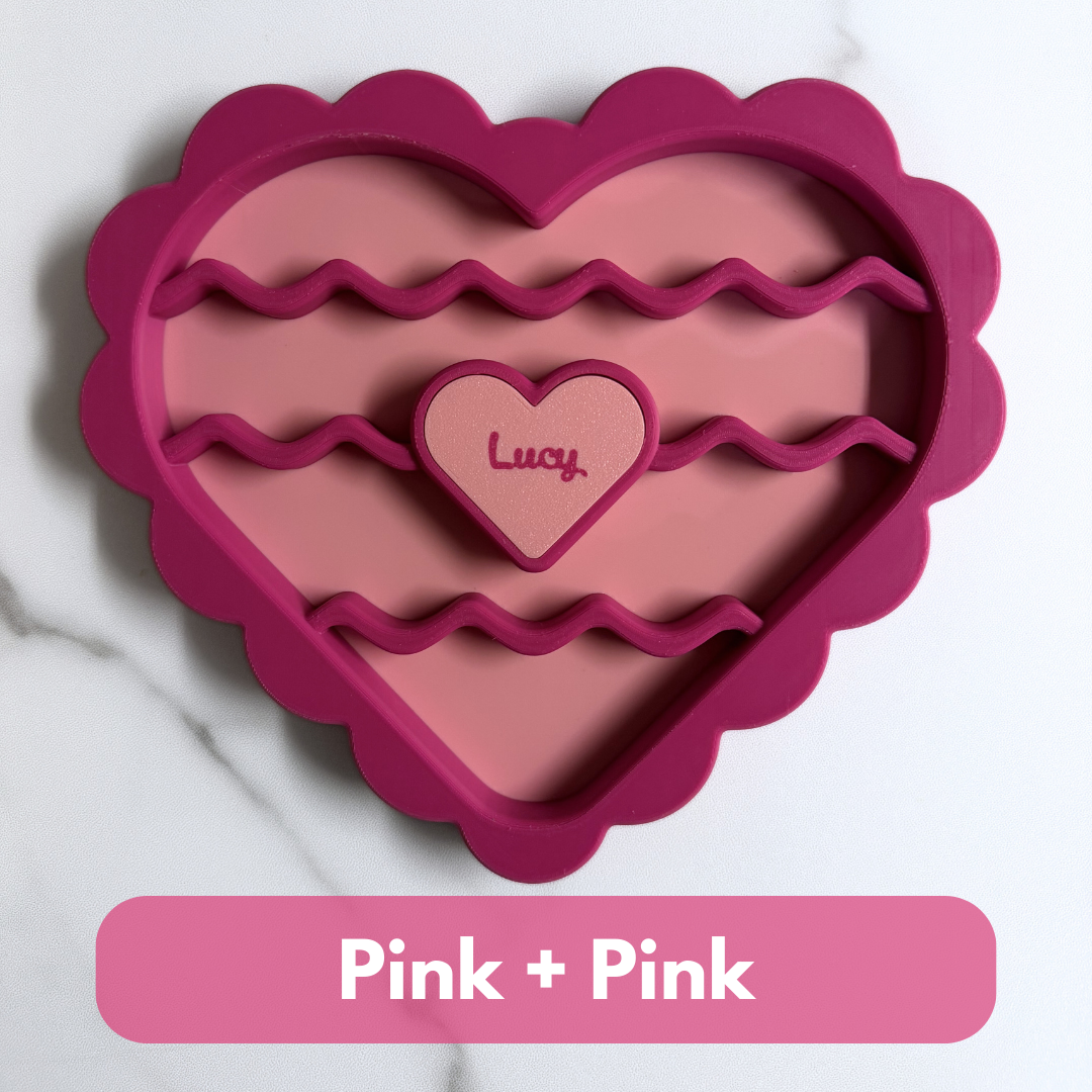Heart-shaped pink cookie cutter with 'Lucy' branding on a white background