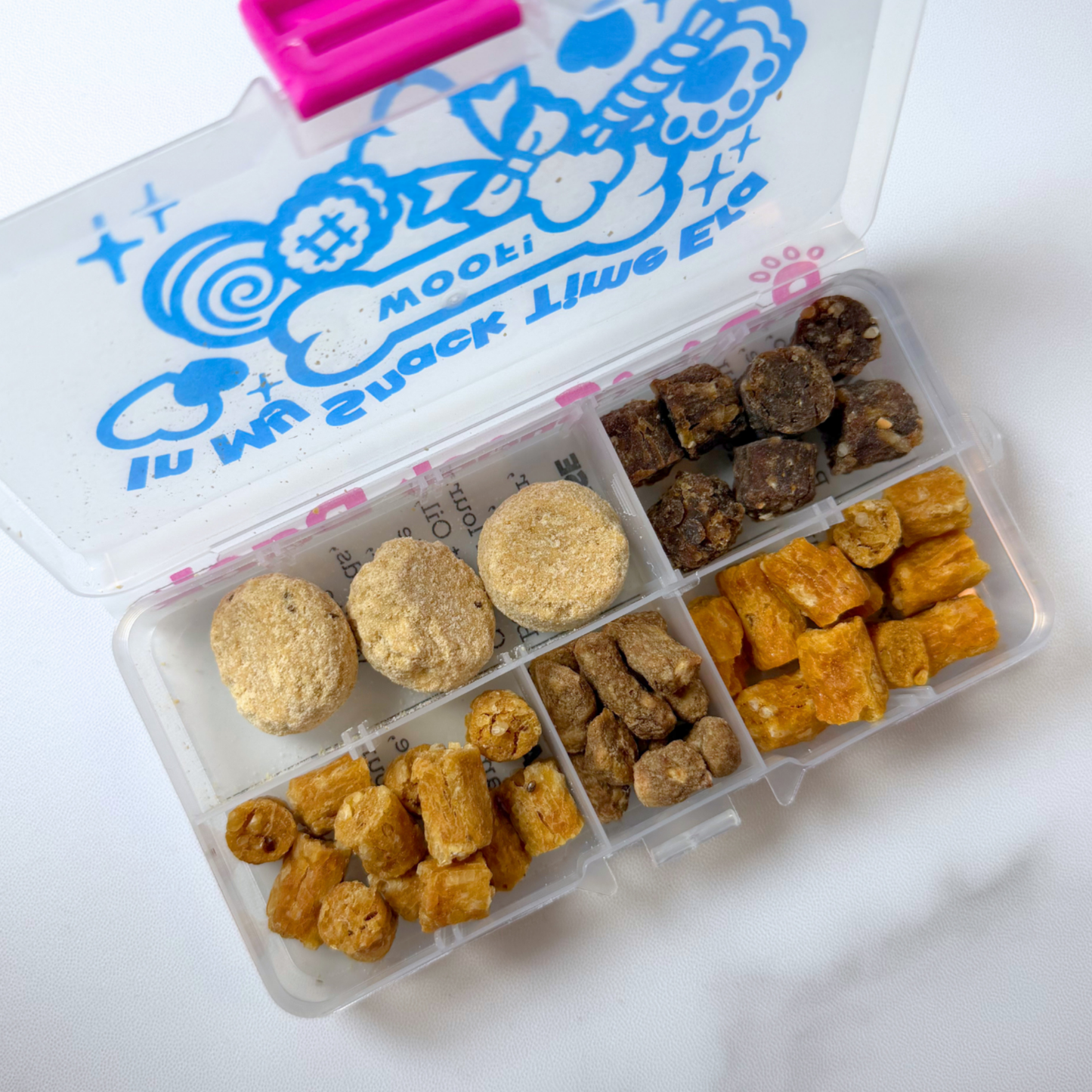 Assorted dog treats in a divided container with a branded lid.