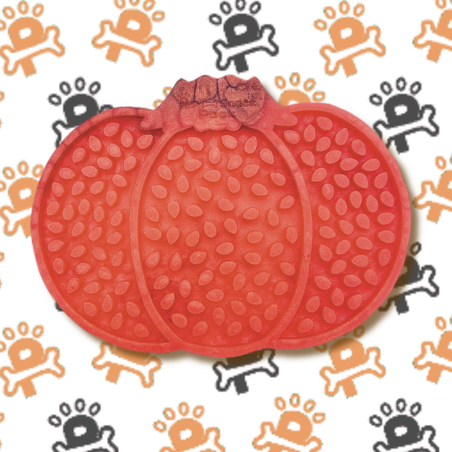 An silicone lick mat shaped like a pumpkin, featuring textured grooves and patterns designed to hold spreads like peanut butter or yogurt for dogs to enjoy