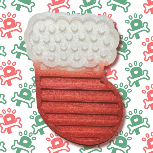 An silicone lick mat shaped like a stocking, featuring textured grooves and patterns designed to hold spreads like peanut butter or yogurt for dogs to enjoy